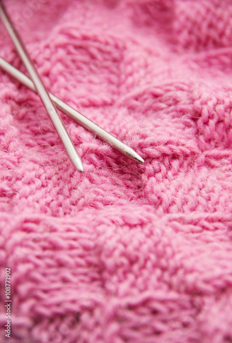 Detail of woven handicraft knit woolen design texture and knitting needle. Fabric pink background © nata777_7