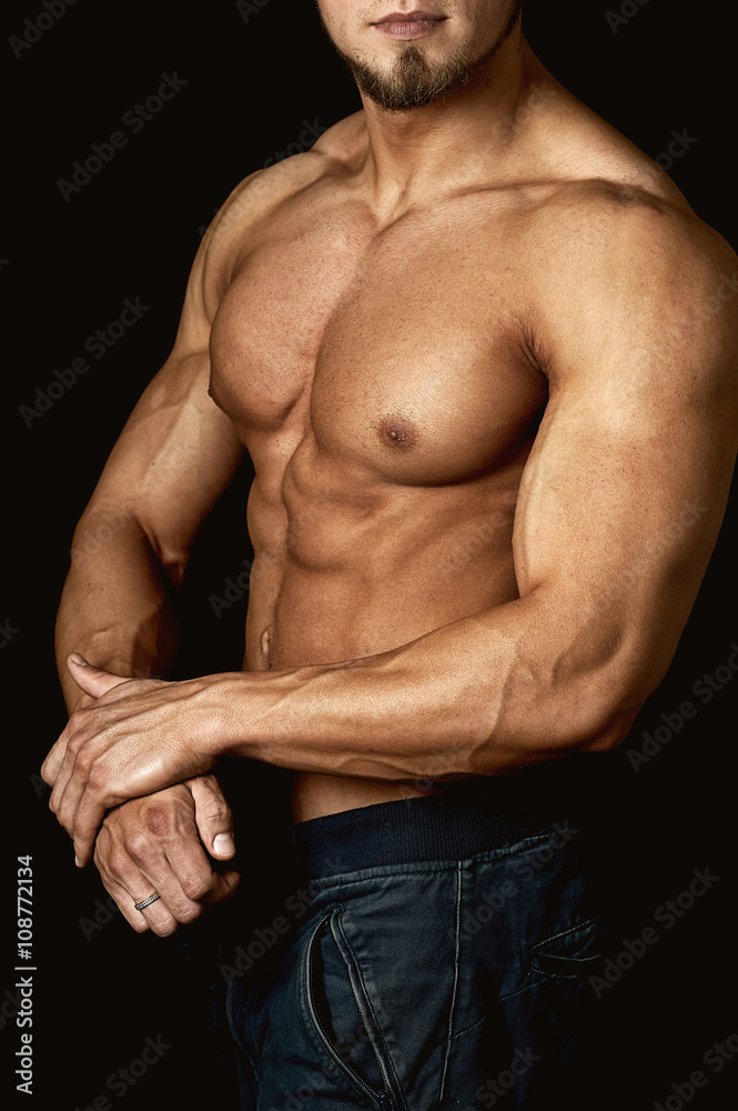 young muscular man showing his body on a dark background young muscular man showing his body on a dark background