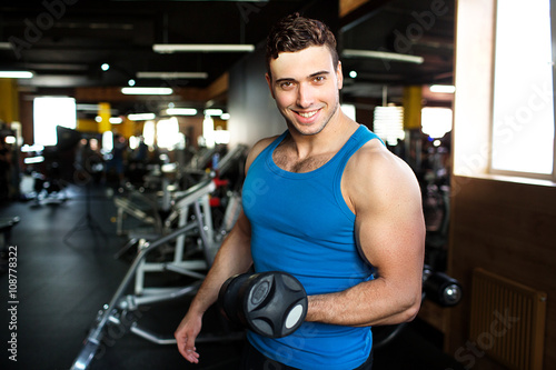 Muscular bodybuilder guy doing exercises with dumbbells.Strong Athletic Man Fitness Model Torso showing six pack abs.Strong Athletic Man Fitness Model Torso showing big muscles