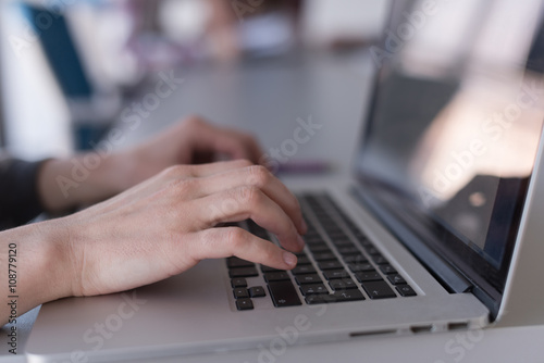 close up of business womans hand typing on laptop with team on m