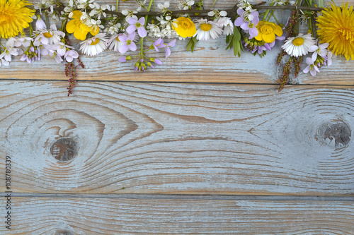 Fototapeta Naklejka Na Ścianę i Meble -  Bunch of fieldflowers,daisies, buttercups, Pentecostal flowers, dandelions  in a border row on a old blue gray spring summer wooden background with empty copy space
