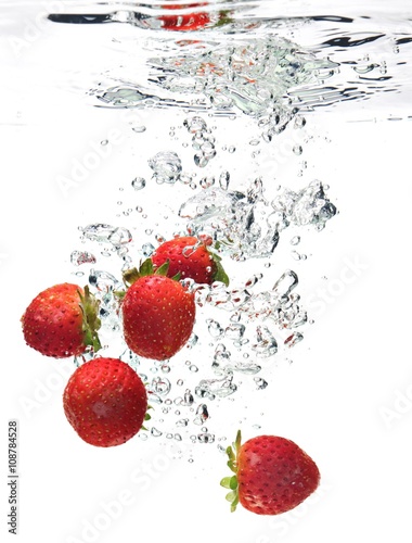 A background of bubbles forming in water after strawberries are dropped into it.