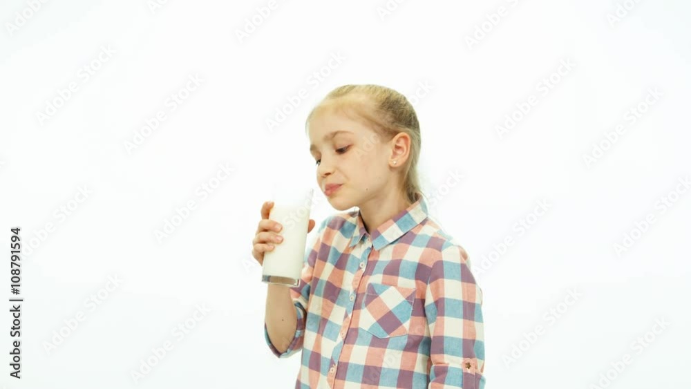 Child girl holding glass and drinking milk and smiling at camera Child girl holding glass and drinking milk and smiling at camera