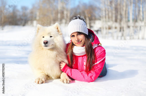 Woman owner with white Samoyed dog lying on snow in winter day © rohappy