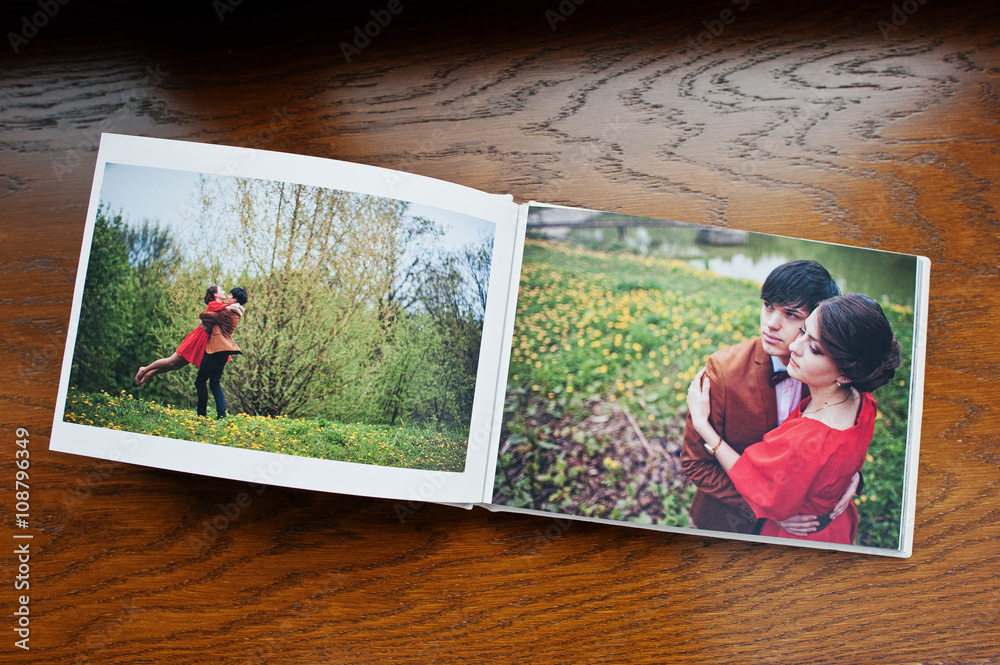 Open pages of album photobook couple in love on wooden backgroun