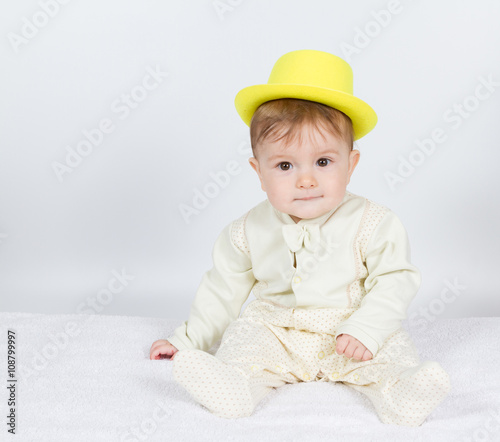 Baby in the yellow hat sits .