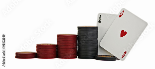 Studio shot of a pair of aces with red and black poker chips, stacked in ascending order, on white background.
