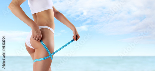 Картината върху платно woman holding blue meter with hands on the thigh, isolated on sea and sky