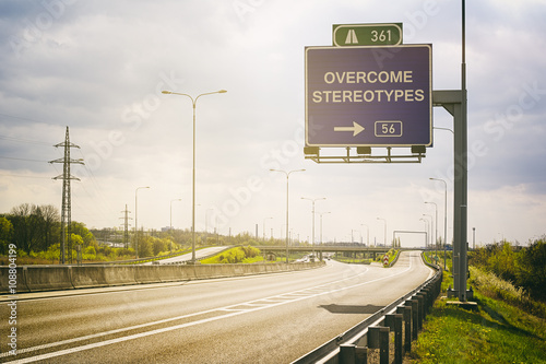 Empty highway and traffic sign above it. Text Overcome Stereotypes - appeal to avoid stereotypes, prejudice and generalization. Sunny positive atmosphere photo