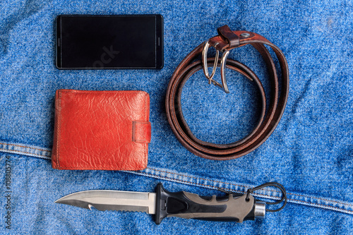 Mobile, a knife, a belt, a wallet on the background of denim.
