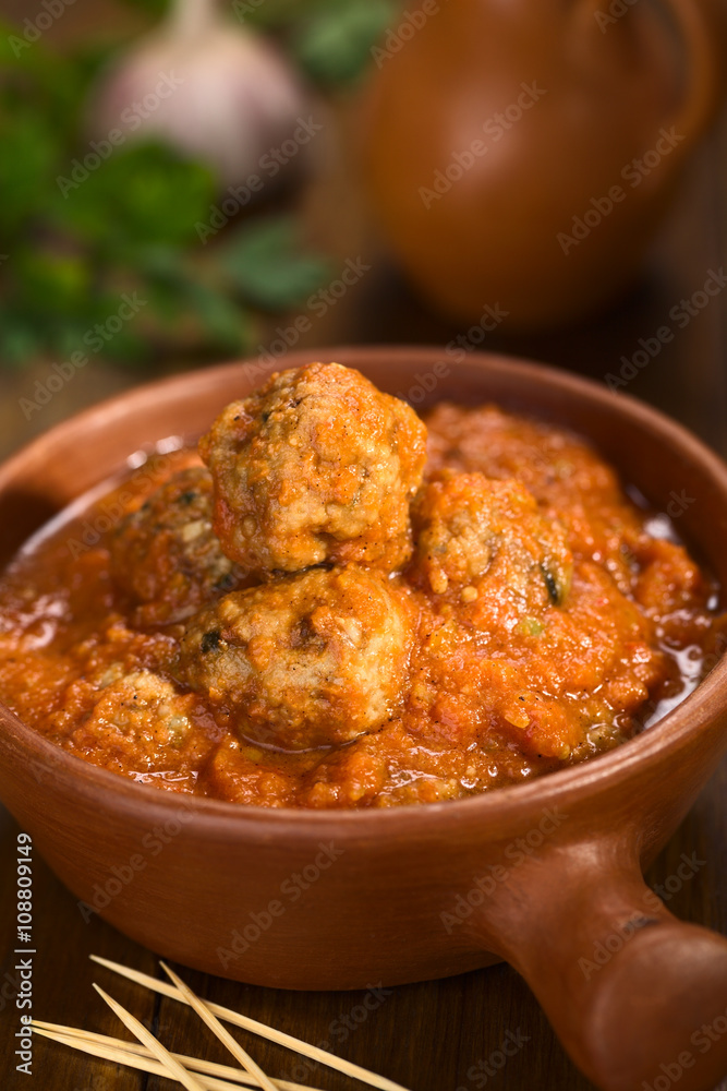 Spanish albondigas (meatballs) in tomato sauce in rustic bowl with toothpick in the front (Selective Focus, Focus on the meatball on the top) Spanish albondigas (meatballs) in tomato sauce in rustic bowl with toothpick in the front (Selective Focus, Focus on the meatball on the top)