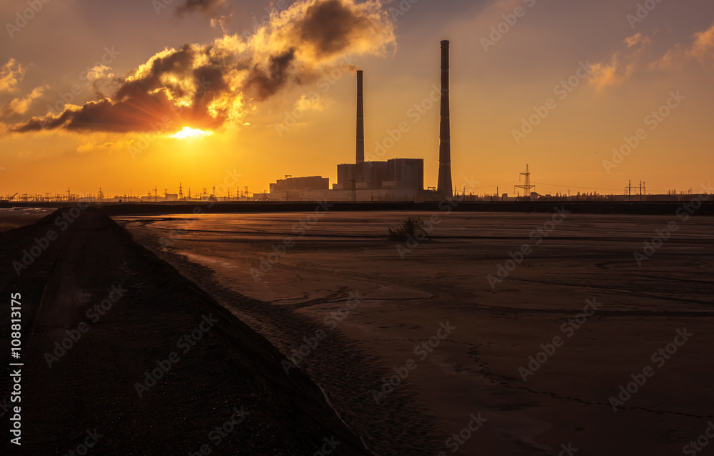 factory with huge chimneys at sunrise. pollution.