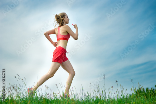 Young lady running. Woman runner running through the summer park rural road. Workout in a park. Beautiful fit girl. Fitness model caucasian ethnicity outdoors. Weight loss exercise. Jogging. © mr.markin