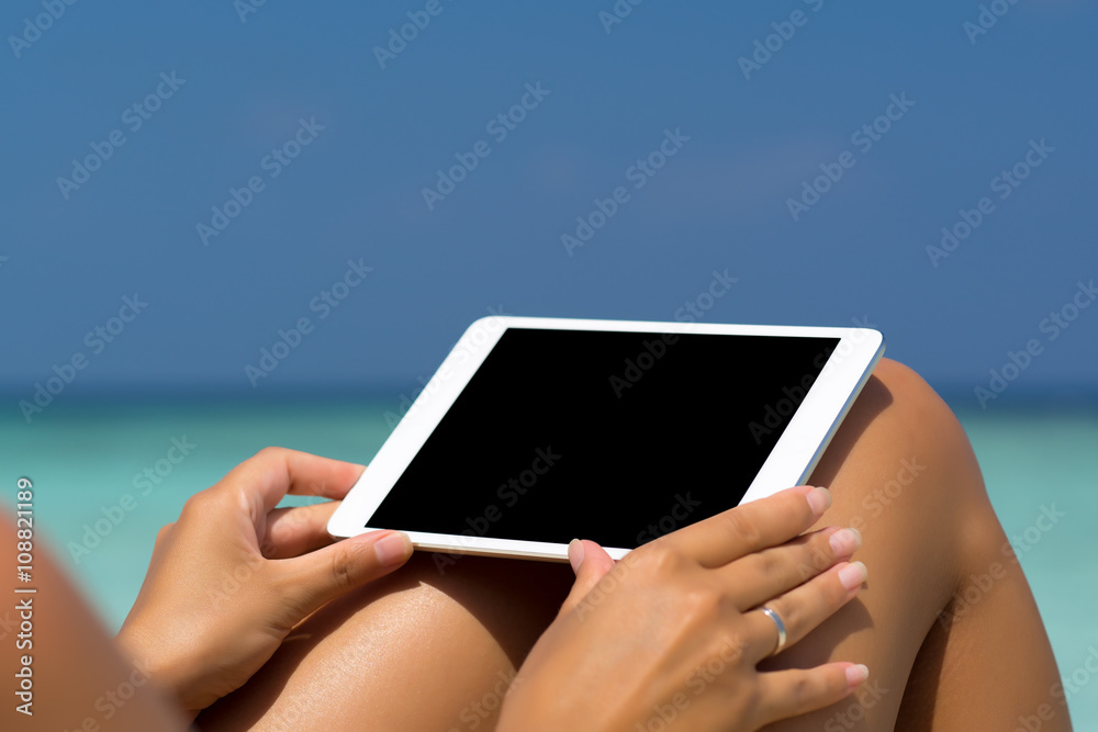 Blank empty tablet computer in the hands of women on the beach Blank empty tablet computer in the hands of women on the beach