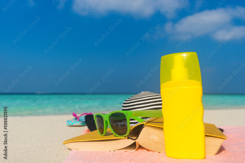Sunscreen, hat and sunglasses on tropical beach Sunscreen, hat and sunglasses on tropical beach