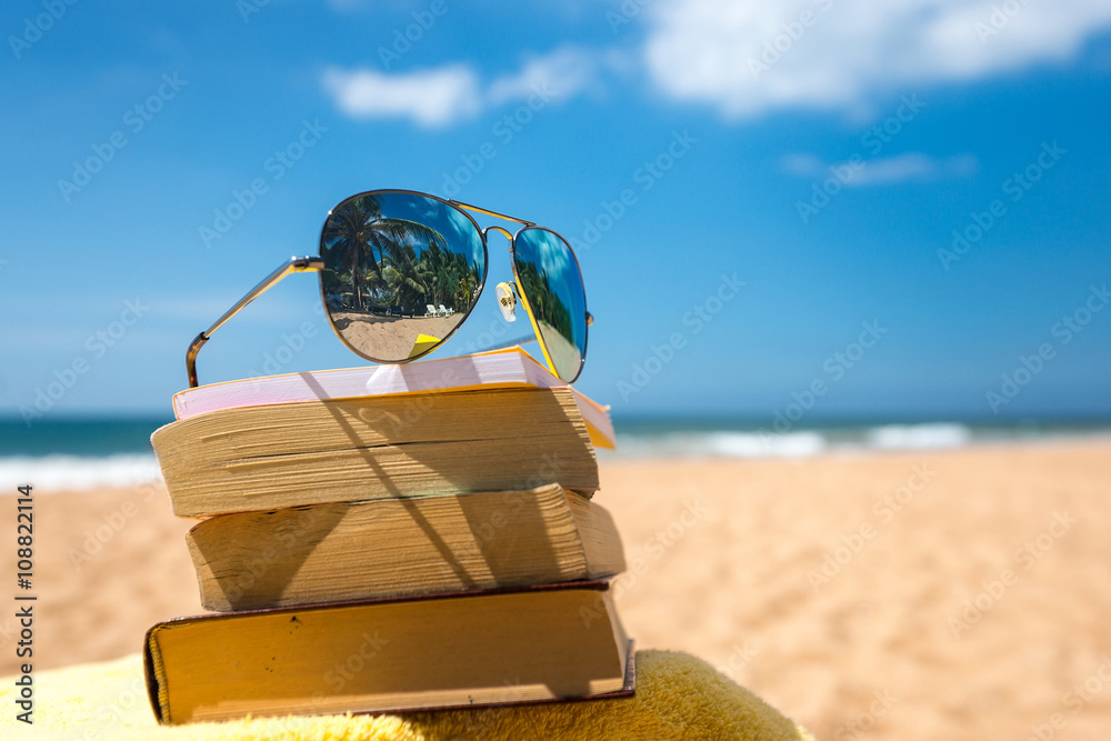 Obraz premium Books and sunglasses on a beach
