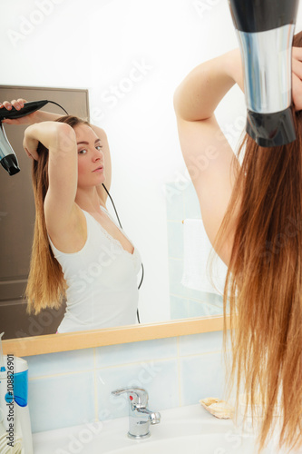 long haired woman drying hair in bathroom