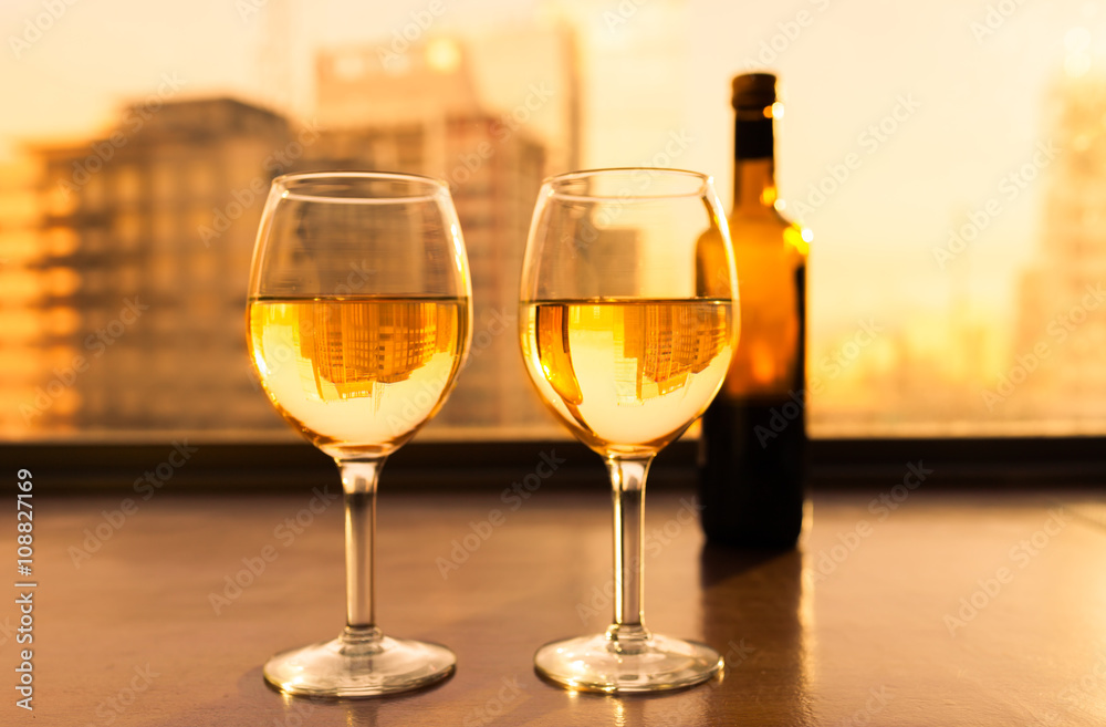 Glasses of white wine and bottle with city view.
Glasses of white wine and bottle with city view.