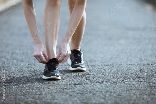 young woman runner tying shoelaces  
