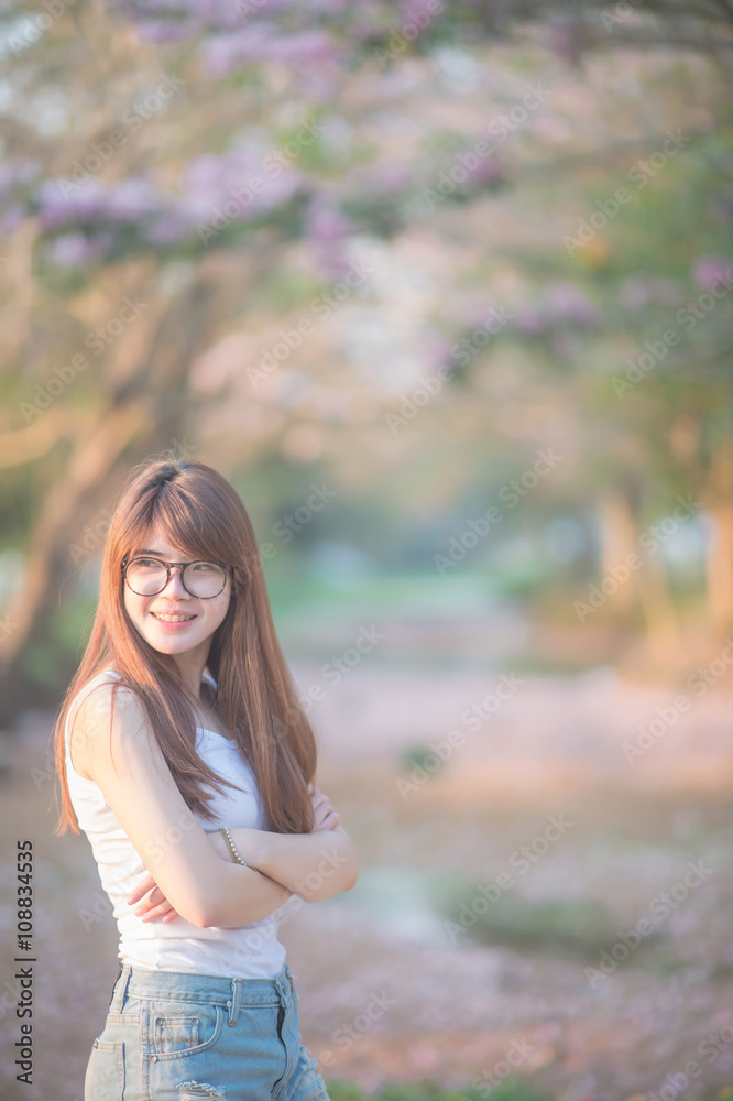 Asian woman  ware glasses with long hair stand in front of  tree  in sunset time