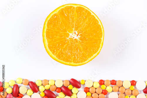 Colorful medical pills and fresh orange on white background  health care and healthy lifestyle concept