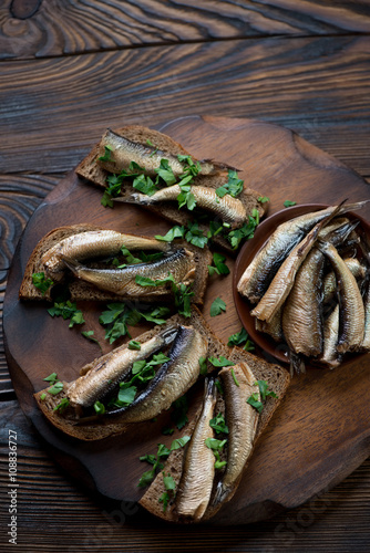 Above view of sandwiches with smoked sprats and parsley, closeup