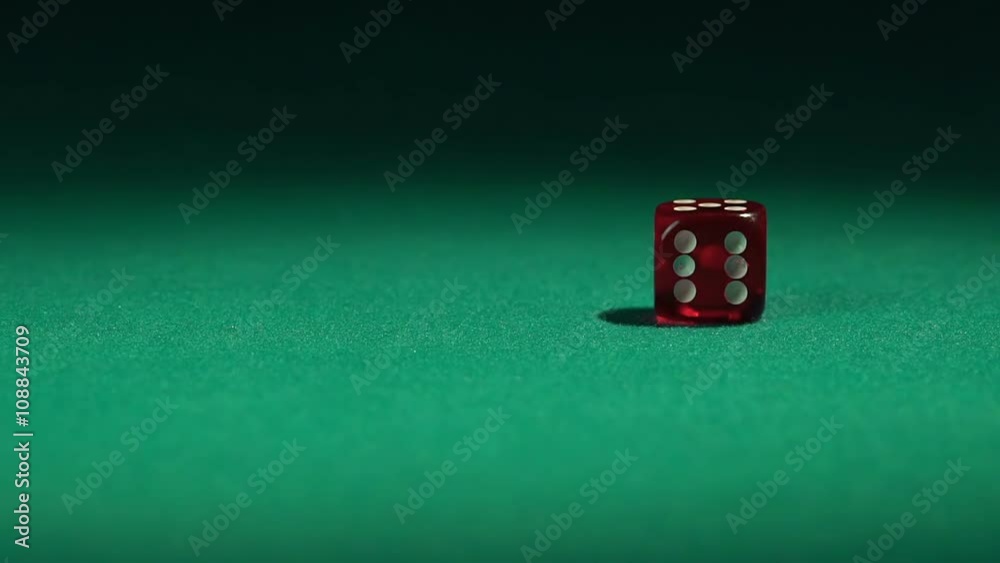 Closeup view of red casino dice rolling on green surface in slow-motion