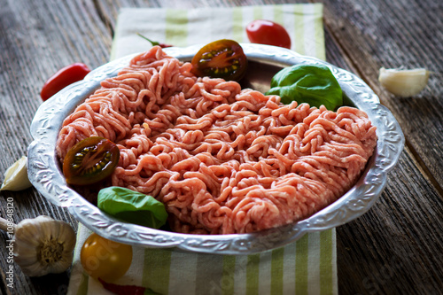 Raw minced meat in a plate close up on a rustic wooden table