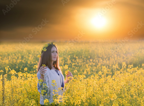 Portrait of a young woman in a rapeseed field. Young joyful girl wearing traditional romanian blouse