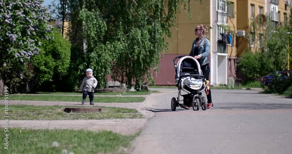 Little Boy With Mother Walking With Baby Carriage Outdoors Little Boy With Mother Walking With Baby Carriage Outdoors