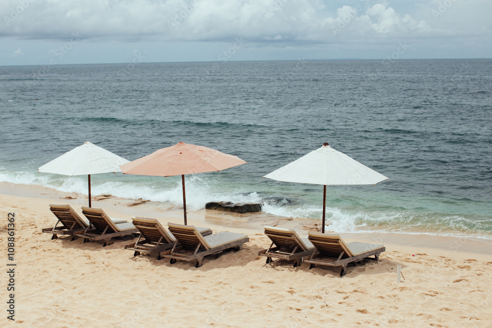 chairs and white umbrella on the beach. Banner