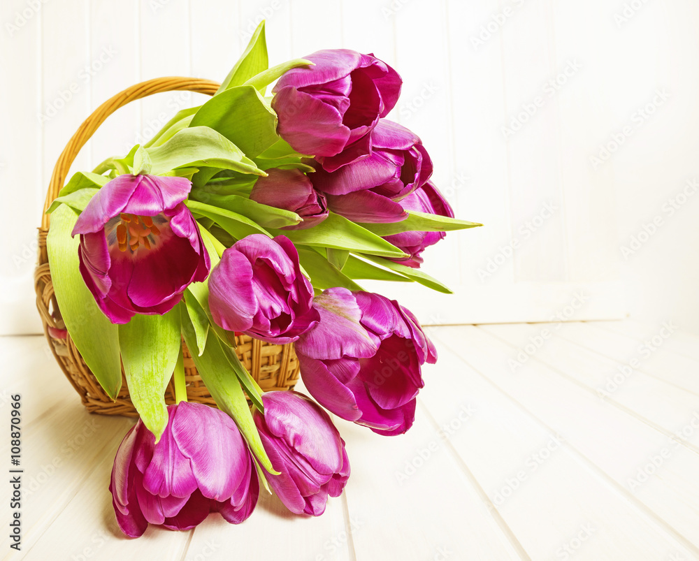 purple tulips in a basket on white wooden table