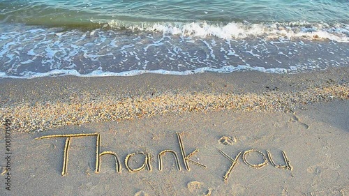 Thank you handwritten in sand on a beach photo