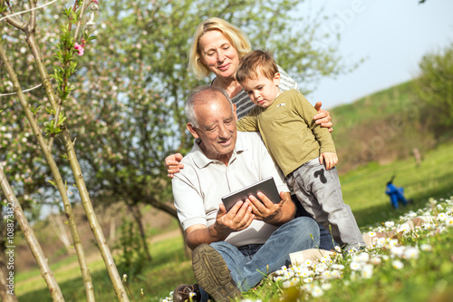 Grandparents with grandson enjoying the sunny spring day outdoors. They are looking something on tablet. © Zoran Zeremski