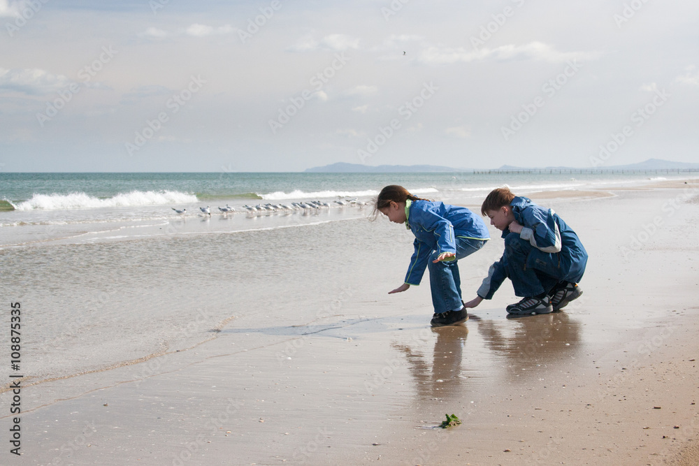 Brother and sister on the beach touching the water. Brother and sister on the beach touching the water.