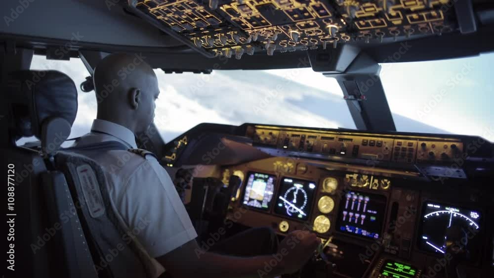 Dramatic side view of 747 cockpit as African American pilot makes a long turn over an area of northern California, USA.  Stabilized hand-held camera, with rack focus from exterior to interior.