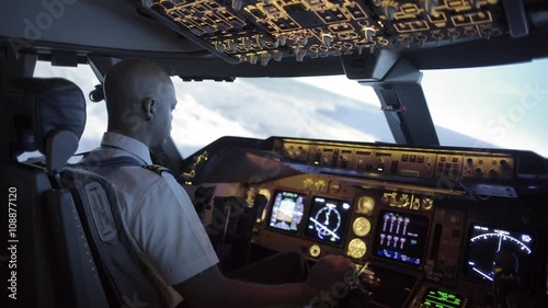 Dramatic side view of 747 cockpit as African American pilot makes a long turn over an area of northern California, USA.  Stabilized hand-held camera, with rack focus from exterior to interior.