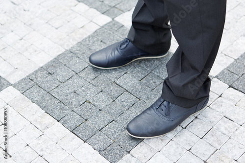 Shoes of a business man on street stones