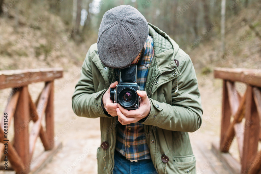 Young man bearded with film photocamera in the forest Young man bearded with film photocamera in the forest