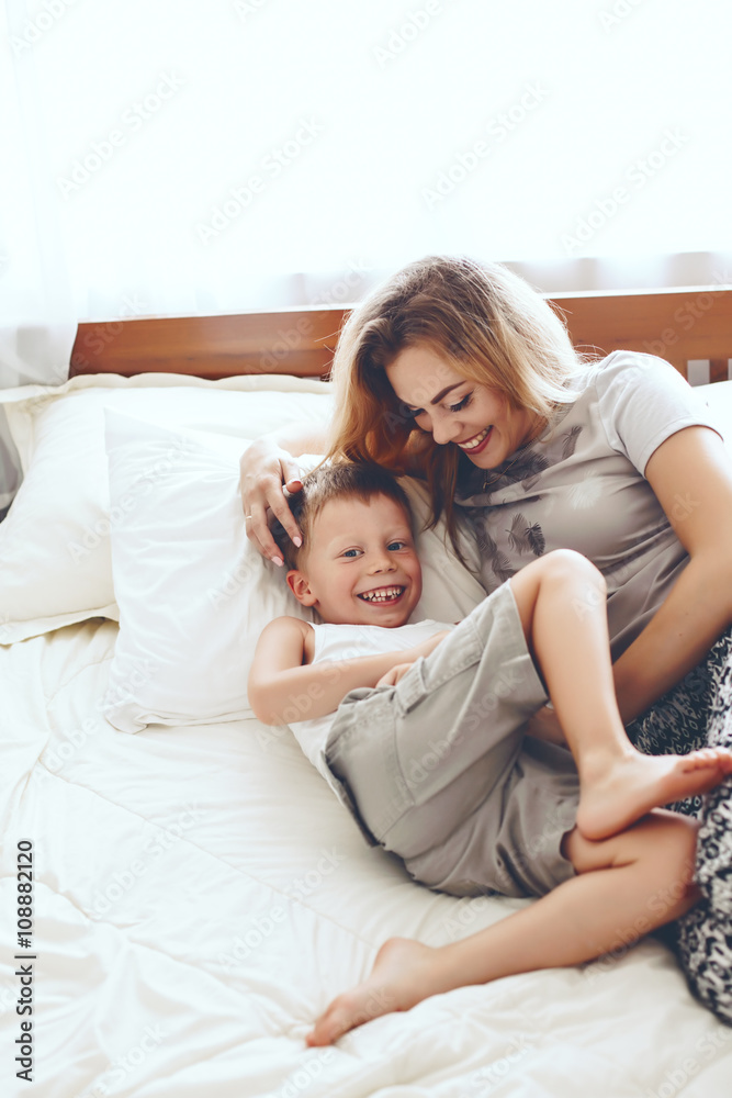 Mother plays with son in bed