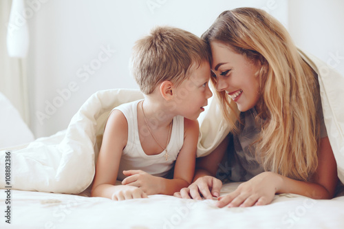 Mother plays with son in bed