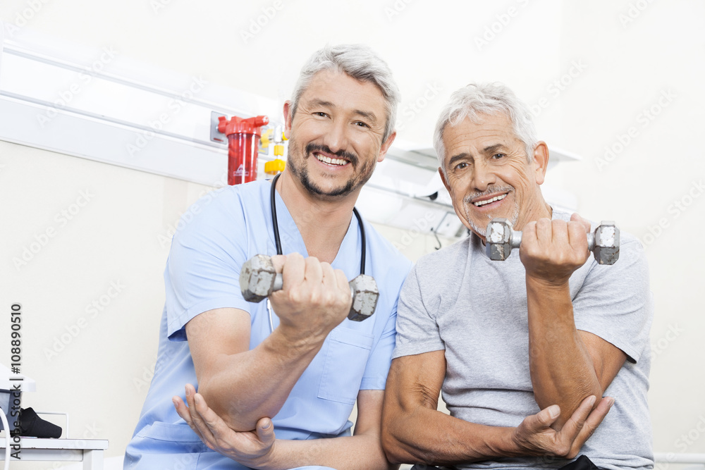 Happy Physiotherapist And Senior Patient Lifting Dumbbells Happy Physiotherapist And Senior Patient Lifting Dumbbells
