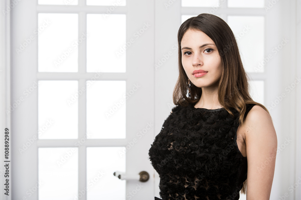 Beautiful woman standing in a black dress over studio loft home interior doors behind Beautiful woman standing in a black dress over studio loft home interior doors behind