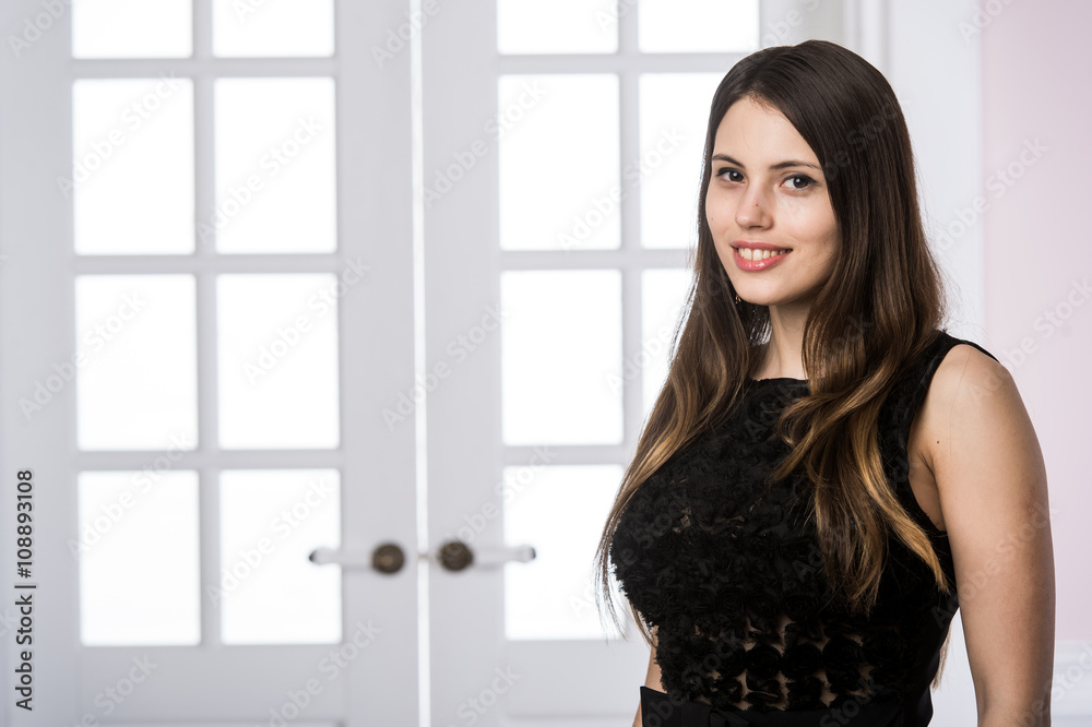 Beautiful woman standing in a black dress over studio loft home interior doors behind Beautiful woman standing in a black dress over studio loft home interior doors behind