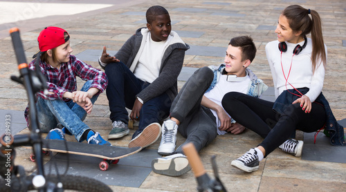 girl and three boys hanging out outdoors and discussing somethin photo