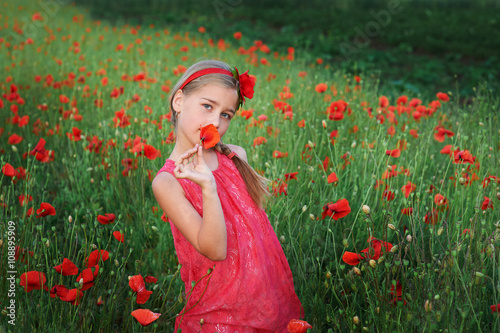 beautiful girl in red dress walks at poppy field