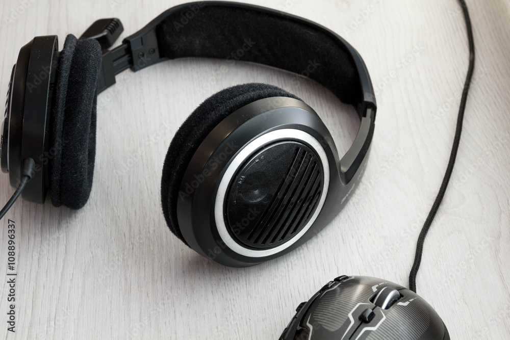 High Angle View of Modern Audio Headphones with Cord and Mouse on Grey Desk Background with Copy Space High Angle View of Modern Audio Headphones with Cord and Mouse on Grey Desk Background with Copy Space