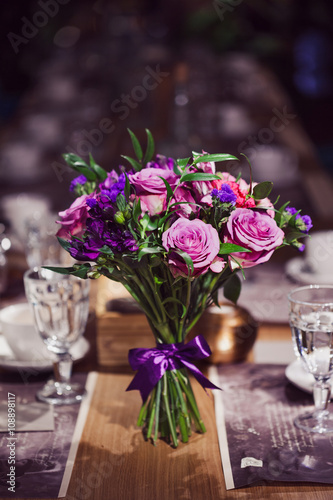 Flowers composition in restaurant,  roses and irises, combination shades of purple
