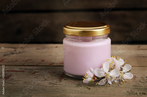 Organic cosmetic cream with apricot tree flowers on a old wooden background. Vintage spa still life.