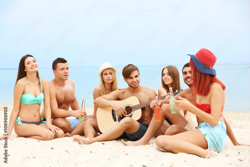 Beautiful young people with guitar having fun on beach